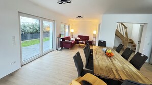 Un vaste espace de vie comprenant une table à manger en bois, des canapés rouges et un escalier menant à un niveau supérieur.