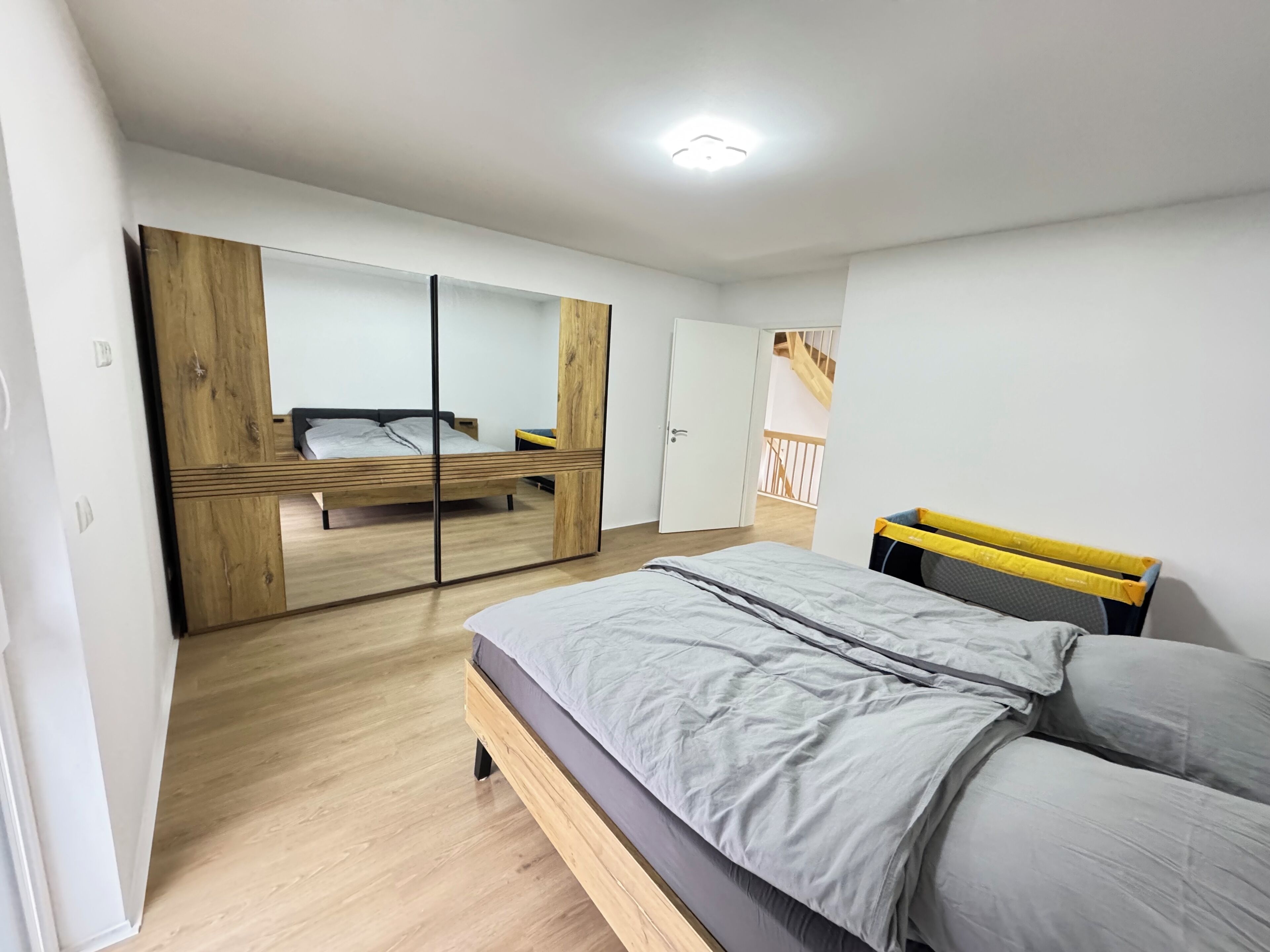 Una camera da letto moderna con un letto, un armadio e uno specchio.