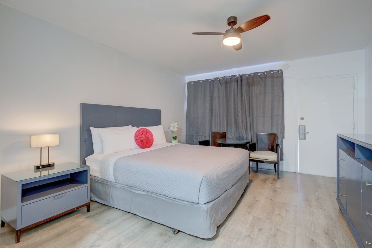 Une chambre à coucher avec un lit, une table de chevet, une chaise et un ventilateur de plafond.