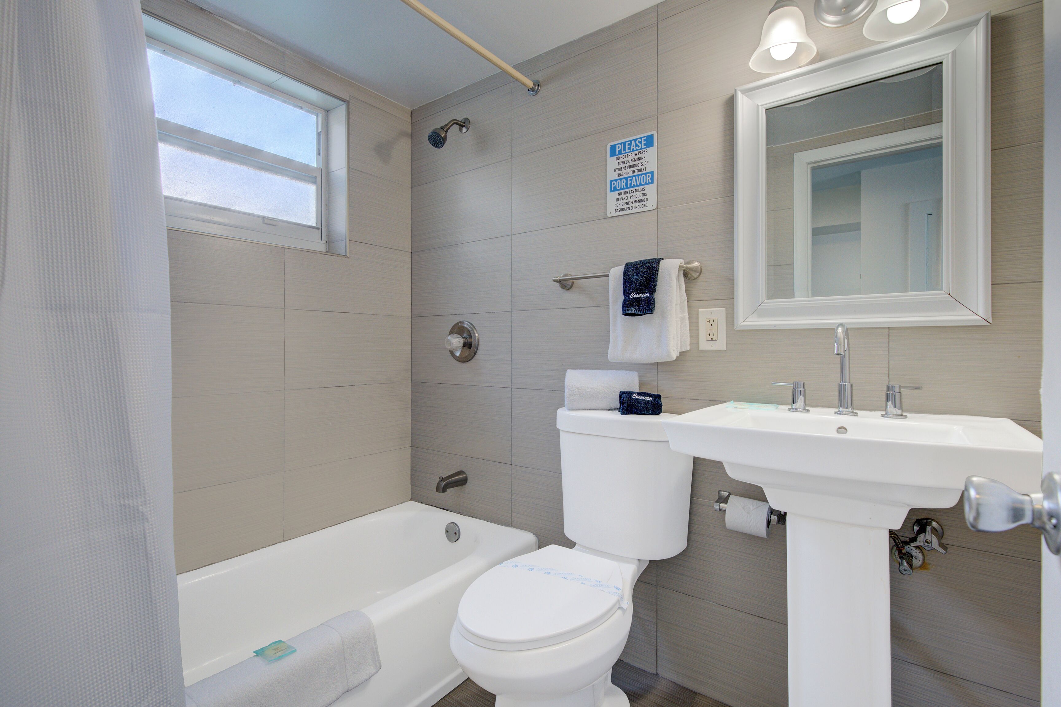 A bathroom with a bathtub, toilet, sink, and a mirror.