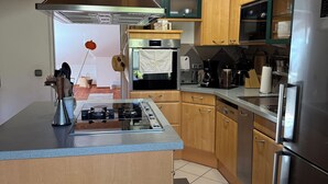 Eine moderne Küche mit Holzausstattung, einem Edelstahlkühlschrank, einem eingebauten Ofen und einem Gasherd.