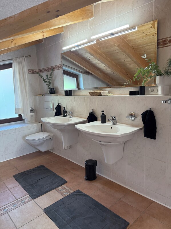 A modern bathroom with two sinks, a toilet, and a mirror. - Soleils Living I Lake & mountains I Lake Starnberg (Berg)