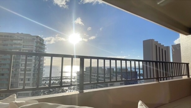 Un balcone con ringhiera in metallo che si affaccia su un panorama urbano, edifici e una distesa d'acqua.