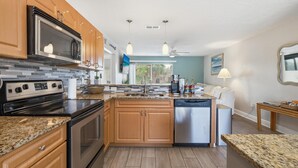 Una cocina moderna con encimeras de granito, electrodomésticos de acero inoxidable, armarios de madera y una isla grande.