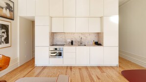 A modern kitchen with white cabinetry, a built-in oven, and a marble backsplash. - VIVA - VIVA Quinta Modernista Flat (Porto)