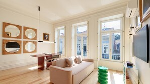 A modern living room with a sofa, a dining table, and multiple windows. - VIVA - VIVA Quinta Modernista Flat (Porto)