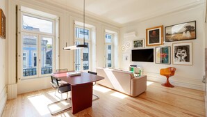 A spacious living area with a dining table, sofa, and a TV on the wall. - VIVA - VIVA Quinta Modernista Flat (Porto)