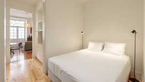 Camera da letto con un letto grande, una scrivania e una sedia in un corridoio.