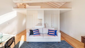 A modern living room with a white sofa, striped pillows, and a glass table. - VIVA Cedofeita Serviced Apartments 11 (Porto)