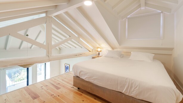 A bedroom with a large bed, wooden ceiling beams, and a skylight. - VIVA Cedofeita Serviced Apartments 11 (Porto)