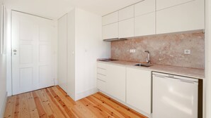 A compact kitchen with white cabinets, a built-in oven, and a dishwasher. - VIVA Cedofeita Serviced Apartments 11 (Porto)