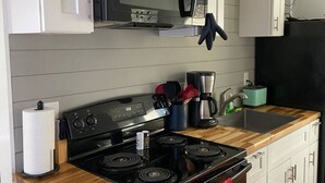 Una cocina moderna con gabinetes blancos, una estufa negra, un microondas y una cafetera.