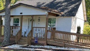 Une petite maison de plain-pied avec un porche, une porte d’entrée et une boîte aux lettres.