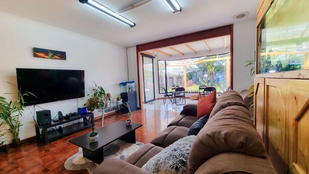 Un salon moderne comprenant un téléviseur à écran plat, un canapé, une table basse et une table avec un plateau en verre, ainsi que des chaises.