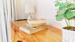 Une table en bois sur laquelle se trouve une pile de livres, une lampe et une plante en pot.