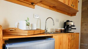 Une cuisine compacte dotée d’un réfrigérateur encastré, de meubles de rangement en bois, d’une machine à café et d’un petit évier.