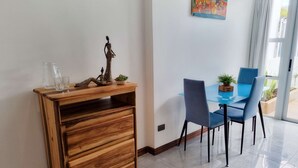 A dining area with a wooden sideboard, a glass table, and blue chairs. - 714 Studios (San José)