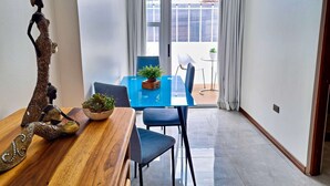 A dining area with a wooden table, blue chairs, and a potted plant. - 714 Studios (San José)