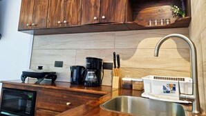 Une cuisine équipée d’un meuble en bois, d’un four à micro-ondes, d’une machine à café, d’un évier et d’un bloc à couteaux.