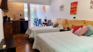 Une chambre d’hôtel avec deux lits, une tête de lit en bois, une petite table, un bureau, une chaise et une fenêtre avec des rideaux.
