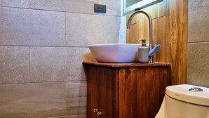 Une salle de bain comprenant des toilettes, un meuble en bois avec un lavabo et un miroir.