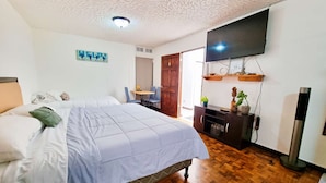 Une chambre à coucher avec un lit, un bureau, une télévision et un plancher en bois.