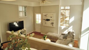 A living room with a television, a ceiling fan, a painting on the wall, and a window.