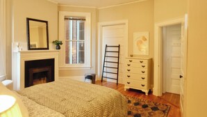A bedroom with a fireplace, a dresser, a ladder, and a door.