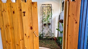 Een houten poort met het getal '7' en een metalen poort met planten in een tuin.