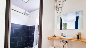 Un baño con ducha, inodoro, lavabo y espejo.