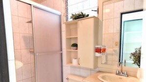 Une petite salle de bain comprenant une douche, des toilettes, un lavabo et des placards de rangement.