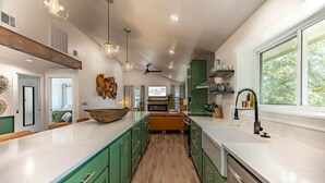 Een moderne keuken met groene kastjes, een groot eiland en een raam voor natuurlijk licht.