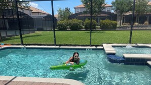 A swimming pool with a person on a green float. - Magical Kingdom of Champions, 6-bed pool home golfing resort close to Disney! (Davenport)
