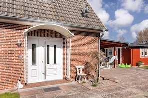 Une maison en briques avec une porte blanche, un petit porche et une sculpture de cheval.