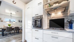 Una cocina moderna con armarios blancos, horno integrado y estufa a gas.