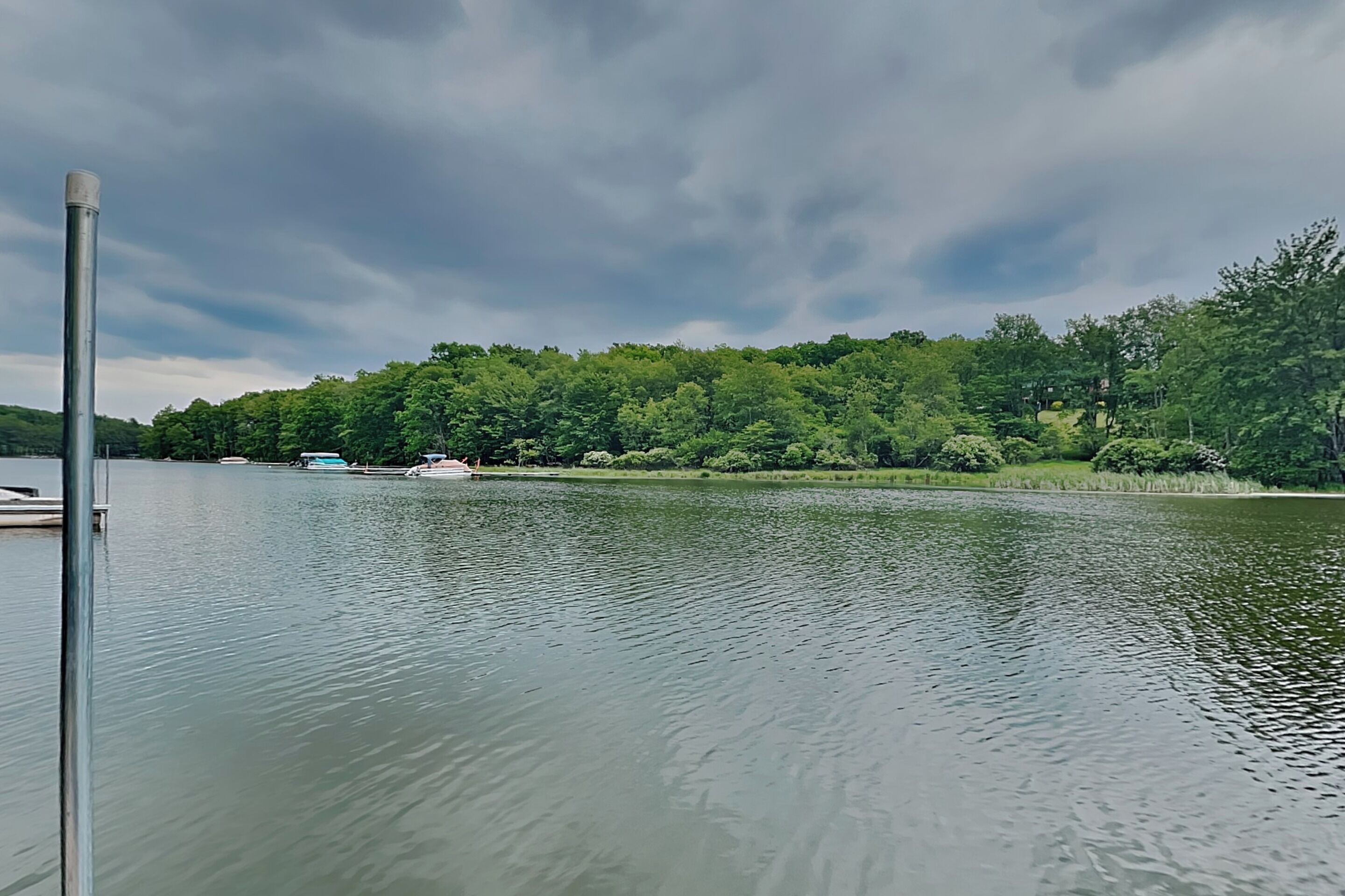 Un lago tranquilo con un muelle y una colina boscosa al fondo.