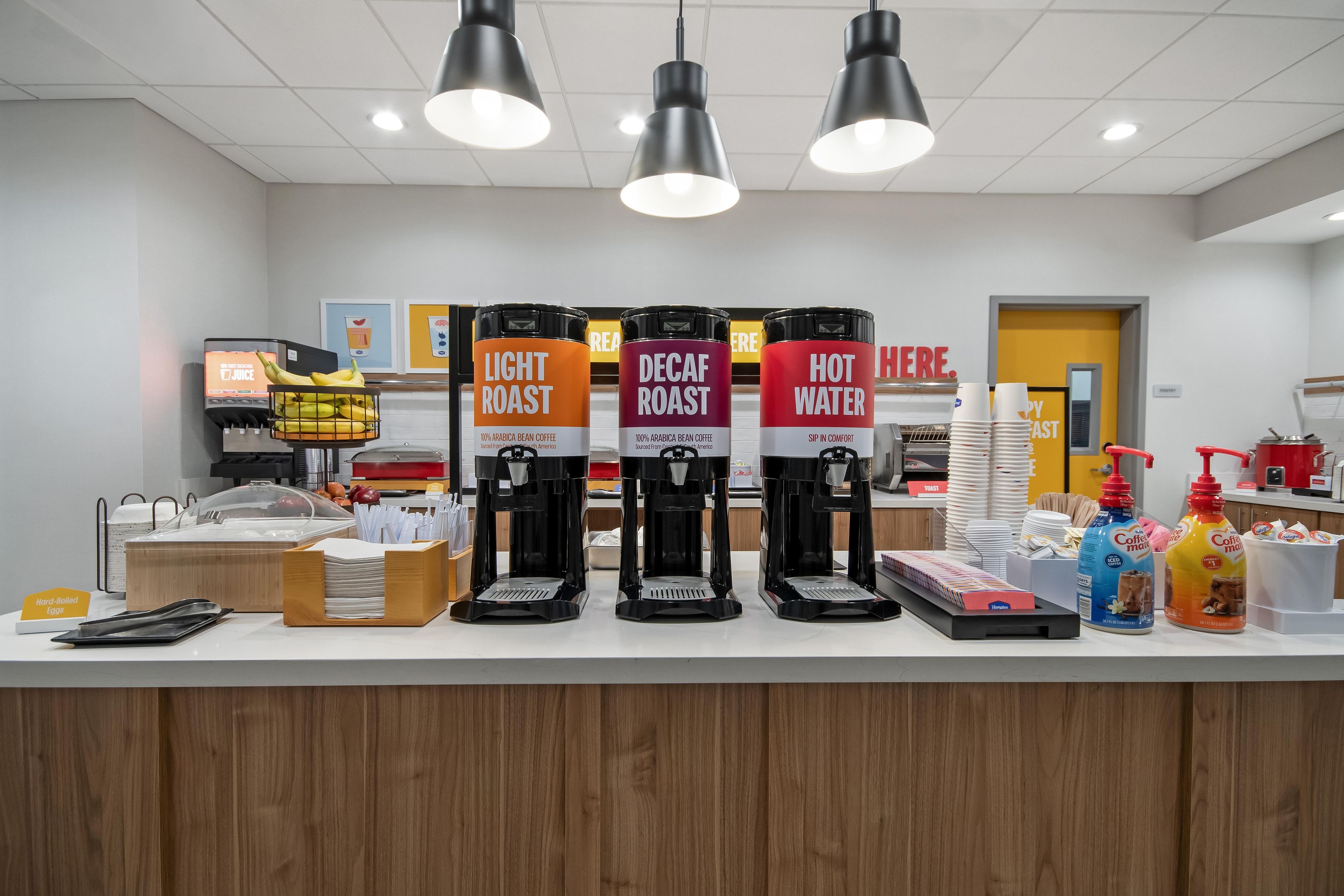 A coffee station with three coffee dispensers labeled 'Light Roast,' 'Decaf Roast,' and 'Hot Water.'
