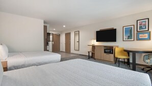 Een hotelkamer met twee bedden, een bureau, een stoel, een televisie en lijstjes met foto's aan de muur.