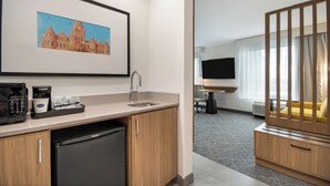 Een moderne hotelkamer met kitchenette, een zithoek, een televisie en een houten ledikant.
