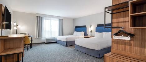 A hotel room with two beds, a desk, a chair, a wardrobe, and a window with curtains.