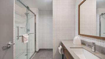 Un baño moderno con cabina de ducha de vidrio, un lavamanos con espejo y azulejos con diseño.