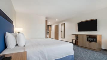 Habitación de hotel con cama, televisión, microondas, escritorio y armario.