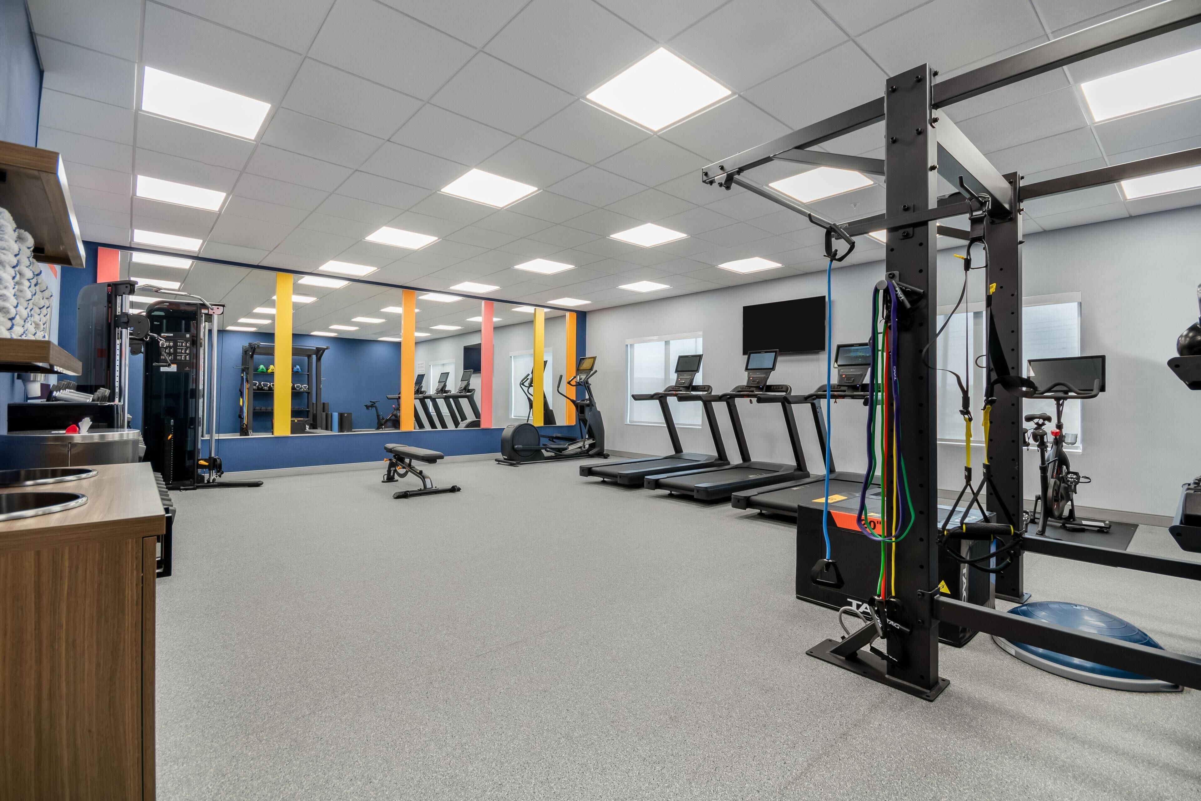 Une salle de sport équipée de tapis de course, de vélos d’exercice et d’appareils de musculation.