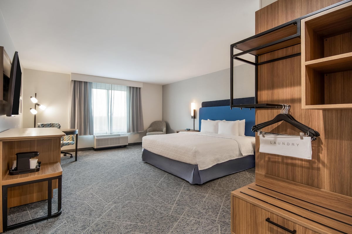 A hotel room with a bed, desk, chair, and a wardrobe with a hanging rack labeled 'laundry'.