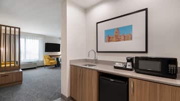 Una habitación de hotel con kitchenette, comedor y cama.