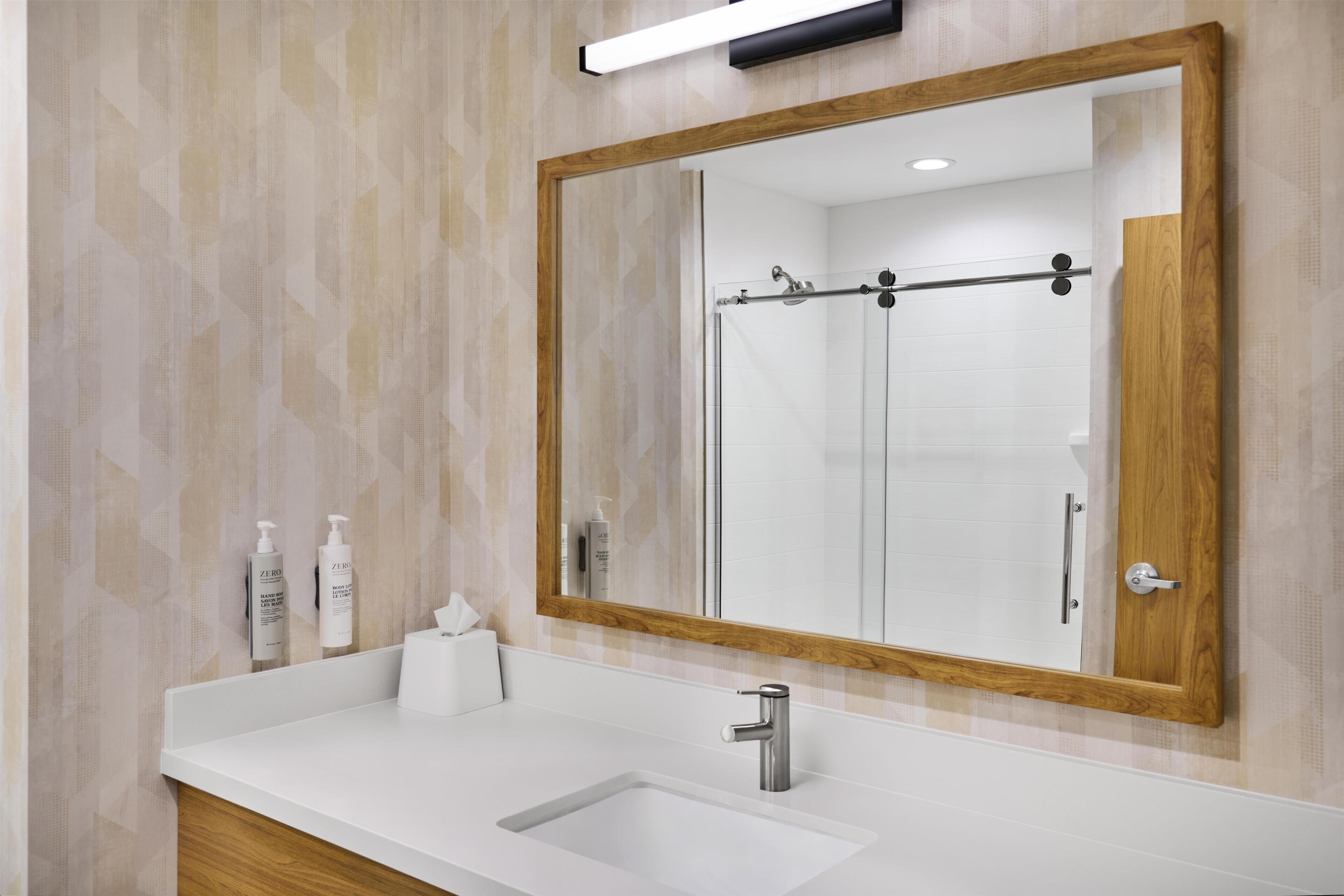 A bathroom with a white sink, a large mirror, and a shower door.