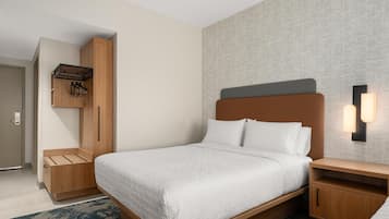 Quarto de hotel com cama, mesas de cabeceira de madeira, guarda-roupa com cabideiro e luminária fixada na parede.