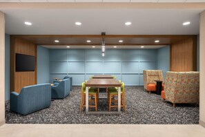 A conference room with a wooden table, blue and orange chairs, and a carpeted floor.