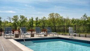 A swimming pool with lounge chairs and a fence.