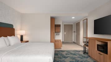 A hotel room with a bed, a TV, a wooden cabinet, and a desk.